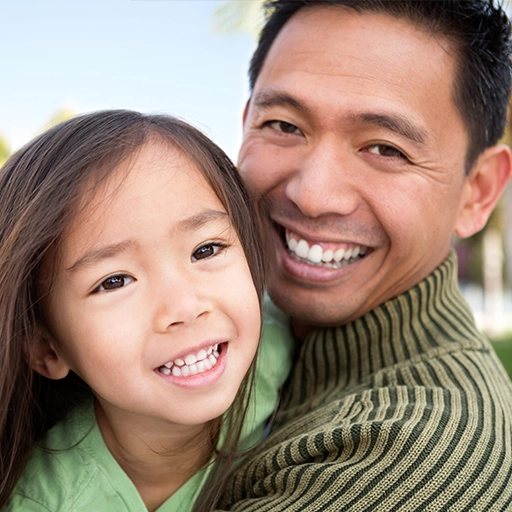A father and his young daughter smiling together