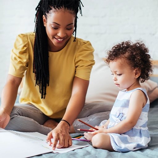 A mother and her toddler daughter coloring together